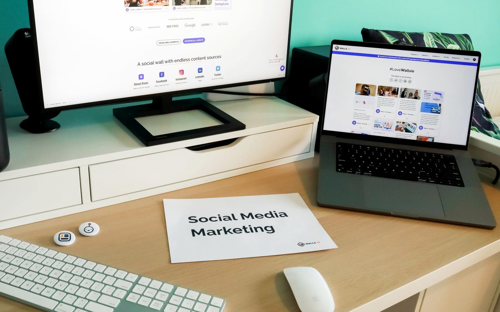 Social media marketing workspace with laptop, monitor, and campaign materials